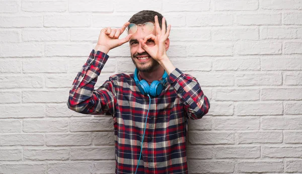 Homem Adulto Jovem Sobre Parede Tijolo Usando Fones Ouvido Com — Fotografia de Stock
