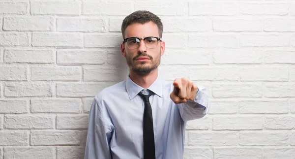年轻的商业男子站在白色砖墙指向相机和你 正面和自信的手势从前面 — 图库照片