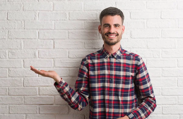 Jonge Volwassen Man Die Witte Bakstenen Muur Lacht Vrolijk Presenteren — Stockfoto