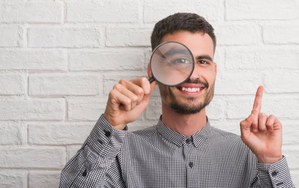 Ung Vuxen Man Över Tegel Vägg Med Förstorande Glas Överraskade — Stockfoto