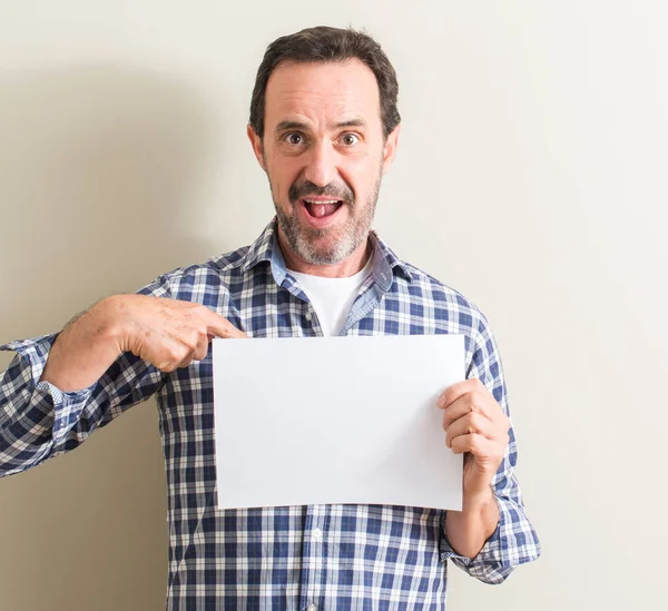 Homem Sênior Segurando Folha Papel Branco Com Rosto Surpresa Apontando — Fotografia de Stock