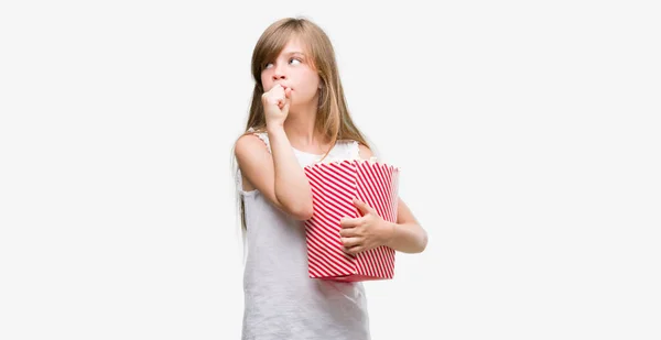 Young Blonde Toddler Holding Popcorn Pack Serious Face Thinking Question — Stock Photo, Image