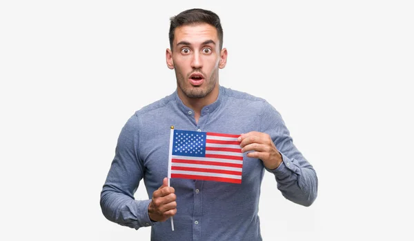 英俊的年轻人拿着美国国旗吓坏了惊讶的脸 害怕和激动与恐惧的表情 — 图库照片