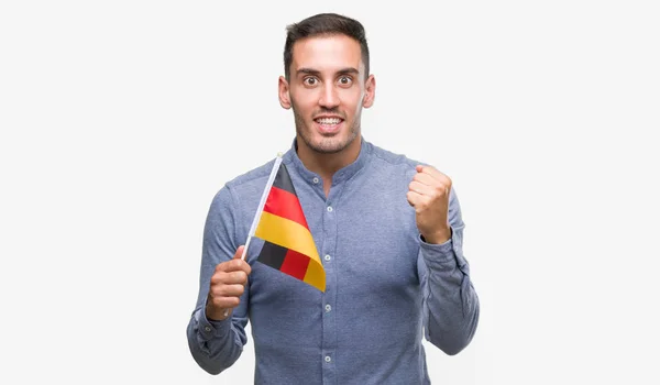 Przystojny Młody Mężczyzna Trzymając Flagę Niemiec Krzyczy Dumny Świętuje Zwycięstwo — Zdjęcie stockowe