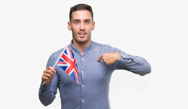 自分自身に驚き顔ポインティング指でイギリスの旗を保持しているハンサムな若い男 — ストック写真