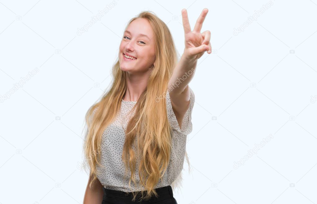 Blonde teenager woman wearing moles shirt smiling looking to the camera showing fingers doing victory sign. Number two.