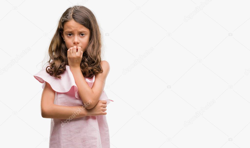 Brunette hispanic girl wearing pink dress looking stressed and nervous with hands on mouth biting nails. Anxiety problem.