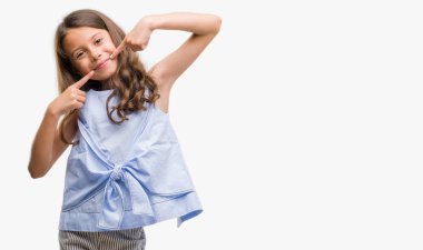 Esmer Latin kız kendinden emin gösterilen ve işaret parmakları diş ve ağız ile gülümseyen. Sağlık kavramı.