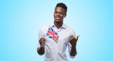 El ve parmak ile yukarı dönük mutlu yüz gülümseyen ile İngiltere bayrak tutan genç Afro-Amerikan adam