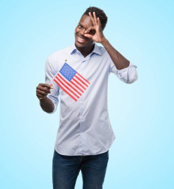 ABD bayrağı ile ok işareti ile el parmaklarının arasından seyir göze yapıyor gülümseyen mutlu yüz tutan genç Afro-Amerikan adam