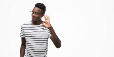 Gözlük ve lacivert t-shirt el ve parmaklar ok işaretiyle yapıyor olumlu gülümseyen giyen genç Afro-Amerikan adam. Başarılı ifade.