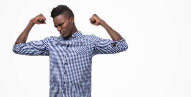 Kol kasları gururlu gülümseyen gösterilen mavi gömlek giymiş genç Afro-Amerikan adam. Fitness kavramı.