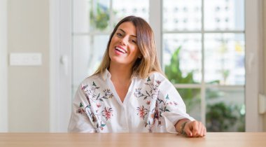 Genç kadınla evde duran ve diş gösterilen kendine güvenen bir gülümsemeyle gülümseyerek mutlu bir yüz