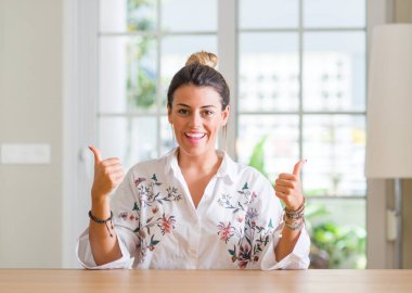 Genç kadın ev başarı işareti başparmak gülümseyen ve mutlu el ile olumlu hareketi yapıyor. Neşeli bir ifadeyle, kazanan jest kameraya bakıyor.