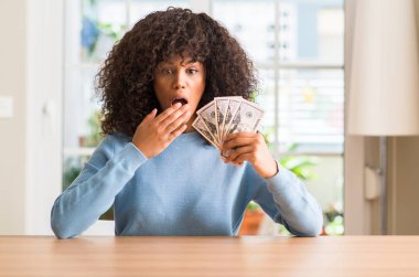 Doları banka notları bir sürpriz yüz, korkuyor ve heyecanlı korku ifadesi ile şok korkmuş tutan Afrikalı-Amerikalı kadın