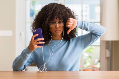 Akıllı telefon kullanan kızgın yüzü, eksi işareti aşağı antipati başparmak ile gösterilen, ret kavramı ile güzel Afrikalı-Amerikalı kadın