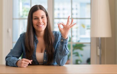 Genç güzel kadın evde parmak, mükemmel sembolü ile ok işareti yapıyor