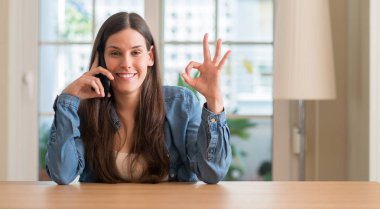 Parmak, mükemmel sembolü ile ok işareti yapıyor akıllı telefon kullanan genç kadın