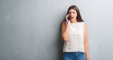 Genç esmer kadın grunge üzerinde gri bir sürpriz yüz, korkuyor ve heyecanlı korku ifadesi ile şok korkmuş Evet duvar