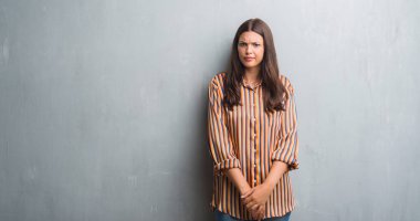 Grunge gri duvar şüpheci ve sinir, papatyanın üzgün sorun nedeniyle genç esmer kadın. Negatif kişi.