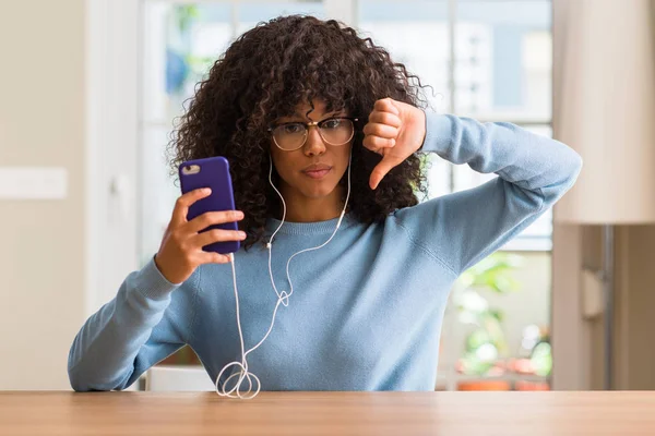 Akıllı telefon kullanan kızgın yüzü, eksi işareti aşağı antipati başparmak ile gösterilen, ret kavramı ile güzel Afrikalı-Amerikalı kadın