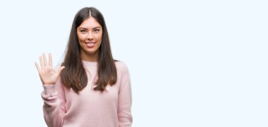 Gösterilen ve parmakları ile işaret Kazak giyen genç güzel İspanyol kadın kendinden emin ve mutlu gülümseyerek süre beş numara.