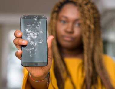 Afrikalı-Amerikalı kadın kendinden emin bir ifade ile kırık smartphone akıllı yüzünde ciddi düşünme gösterilen