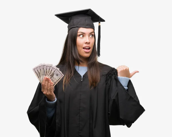 Mujer Hispana Joven Con Uniforme Graduado Sosteniendo Dólares Señalando Mostrando — Foto de Stock