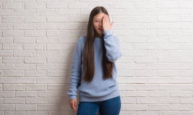 Beyaz tuğla duvar kaplama el yüz ve sürpriz duygu kendinden emin gülümseme ile tek gözlü kadın genç Chinise.