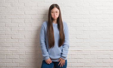 Genç Chinise kadın komik surat ile yanakları şişirme beyaz tuğla duvarın üzerinden. Ağız ile hava, deli ifade şişirilmiş.