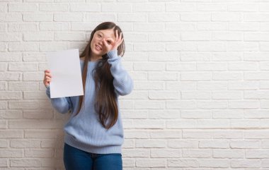 Mutlu yüz el parmaklarının arasından seyir göz üzerinde ok işaretiyle yapıyor gülümseyen ile boş kağıt tutan tuğla duvarın üzerinden Genç Çinli kadın