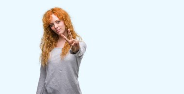 Zafer işareti yapıyor parmak gösterilen kamera seyir gülümseyen genç Kızıl saçlı kadın. İki numaralı.