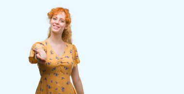 Tebrik ve konuksever dost sunan karşılıklı gülümseyen genç Kızıl saçlı kadın. Başarılı iş.