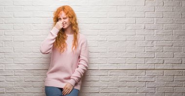 Duran bir şey pis ve iğrenç kokulu tuğla duvar, dayanılmaz koku, holding nefes burun parmaklar ile genç Kızıl saçlı kadın. Kötü kokuyor kavramı.