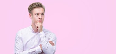 Genç yakışıklı sarışın adam ciddi bir yüz düşünme hakkında soru, çok karışık bir fikir