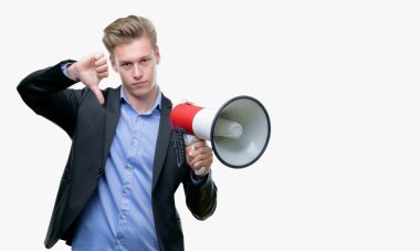 Genç yakışıklı sarışın adam kızgın yüzü, eksi işareti aşağı antipati başparmak ile gösterilen, ret kavramı ile bir megafon holding