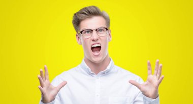 Genç yakışıklı sarışın adam çılgın ve kızgın bağırarak ve agresif ifade ve silah kaldırdı bağırıyordu. Hayal kırıklığı kavramı.