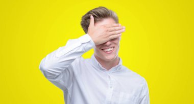 Gülümsüyor ve gözleri için sürpriz kapsayan yüz el ile gülüyor genç yakışıklı sarışın adam. Kör kavramı.