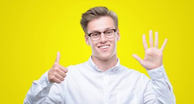 Gösterilen ve parmakları ile işaret genç yakışıklı sarışın adam kendinden emin ve mutlu gülümseyerek süre 6 numara.