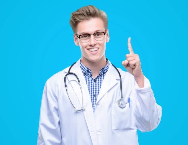 Genç yakışıklı sarışın doktor bir fikir ya da soru işaret parmağı ile gülen yüz, sürpriz bir numara