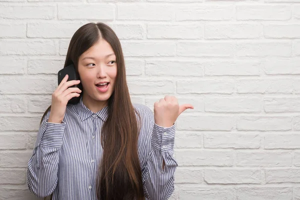 Молодая Китаянка Кирпичной Стеной Разговаривает Телефону Указывая Показывая Пальцем Вверх — стоковое фото