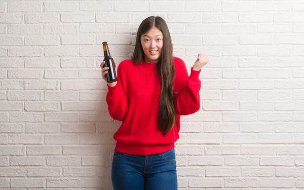 Joven Mujer China Sobre Pared Ladrillo Bebiendo Cerveza Gritando Orgulloso — Foto de Stock