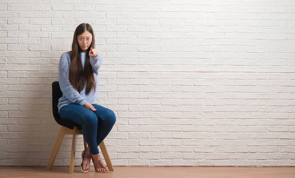 Jonge Chinese Vrouw Zit Stoel Bakstenen Muur Met Vinger Wijzen — Stockfoto