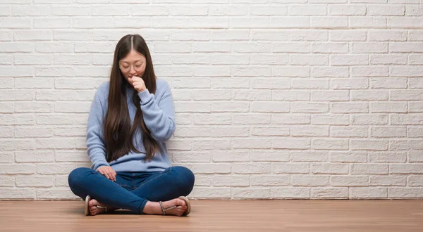 年轻的中国妇女坐在地板上的砖墙感觉不适和咳嗽作为症状的感冒或支气管炎 医疗保健理念 — 图库照片