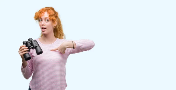 Mujer Pelirroja Joven Mirando Través Prismáticos Con Cara Sorpresa Señalando — Foto de Stock