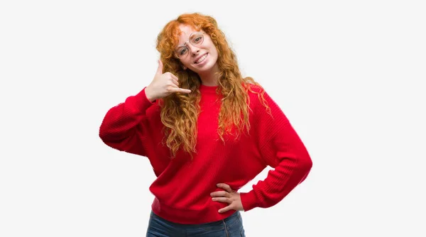 笑みを浮かべて赤いセーターを着ている若い赤毛の女性の手と電話で話しているように指で電話のジェスチャーを行います 通信の概念 — ストック写真