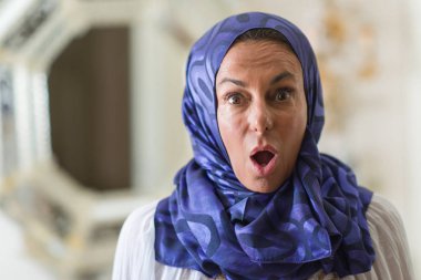 Renkli hijab bir sürpriz yüz, korkuyor ve heyecanlı korku ifadesi ile şok korkmuş giyen orta yaş esmer Arap kadın