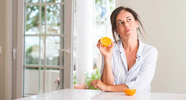 Donna Mezza Età Possesso Frutta Arancione Faccia Seria Pensando Alla — Foto Stock