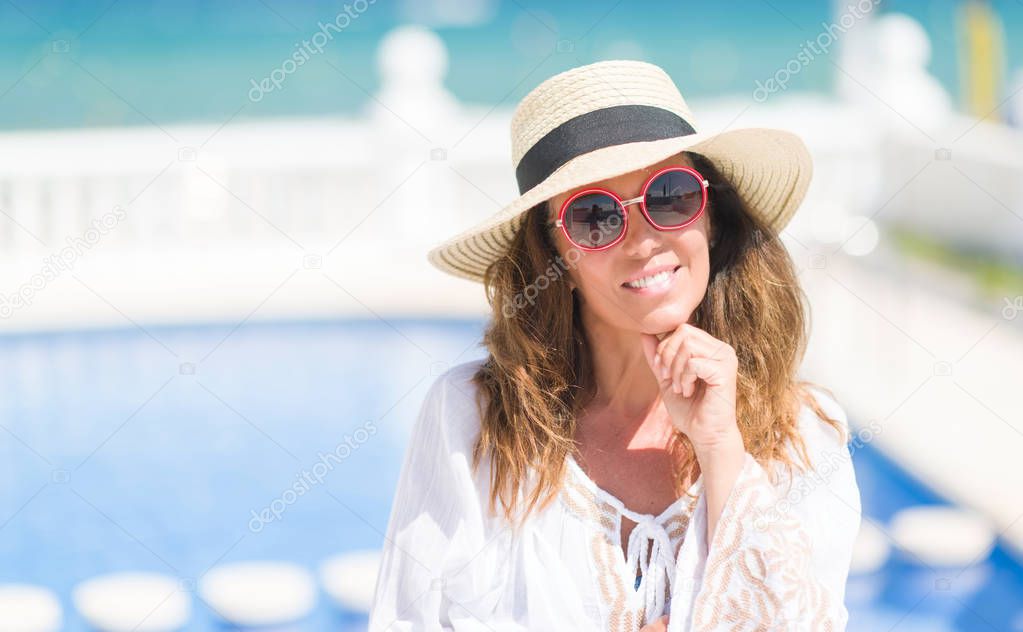 Middle age brunette woman by the swiming pool serious face thinking about question, very confused idea