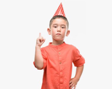 Bir fikir ya da soru işaret parmağı ile gülen yüz, bir numara koyu saçlı küçük çocuk Doğum günü şapkası şaşırttı